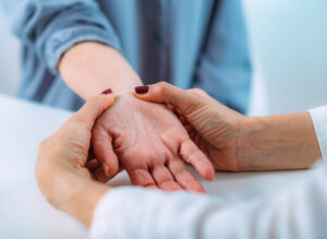 A healthcare provider's hands touching a patient's wrist.