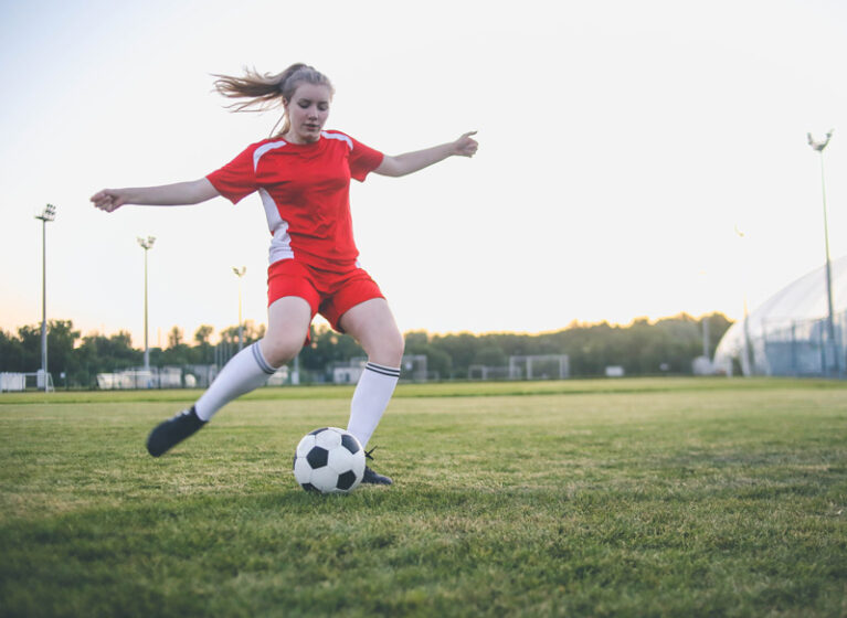 Girl playing soccer as part of school team