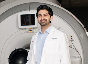 Shayan Moosa, MD, stands in front of a focused ultrasound machine