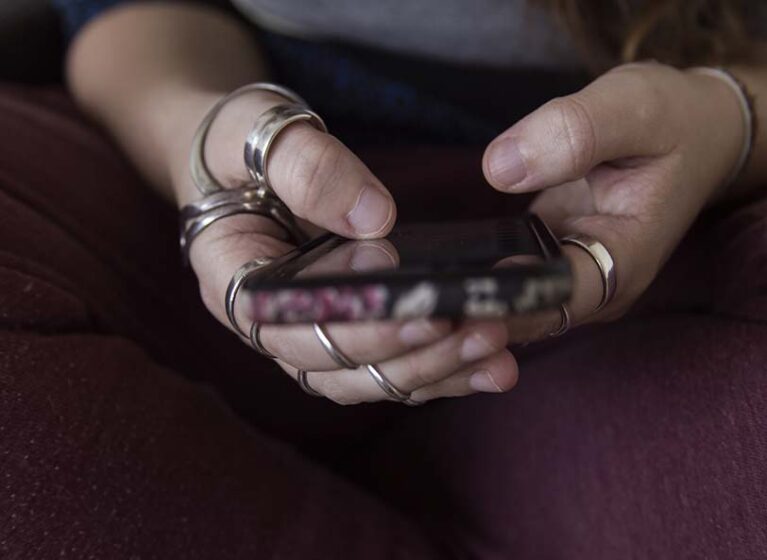 Young woman with ring splints looks at phone